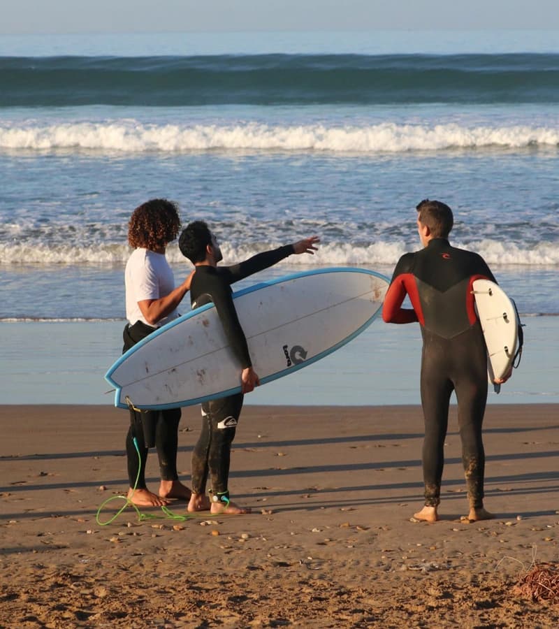 Surfers with boards heading into the waves at Taghazout
