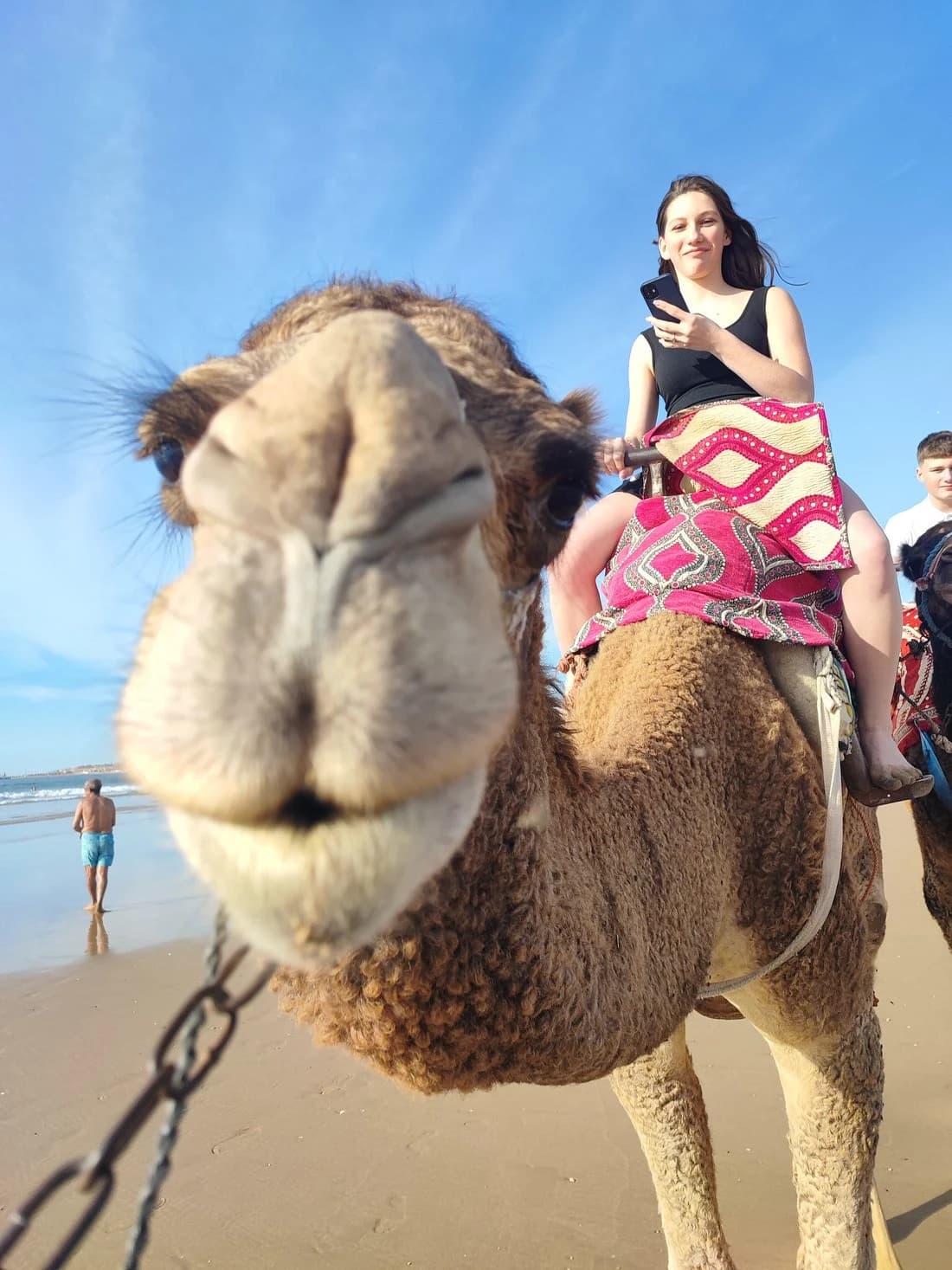 Smiling guest riding a camel on the beach
