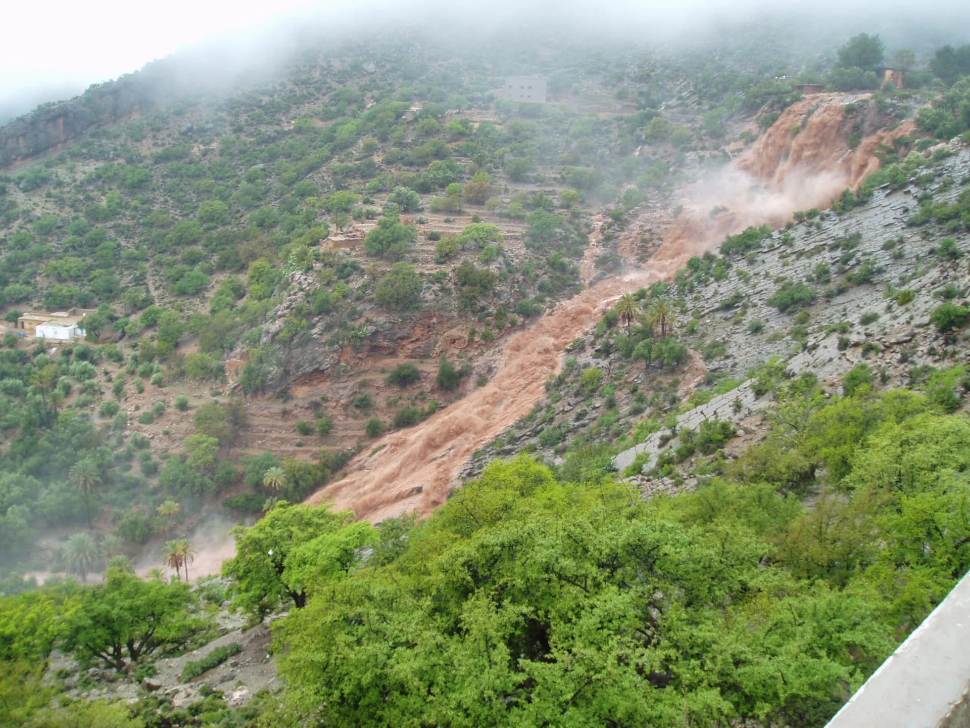 Brown cascade running down the mountainside into the green valley