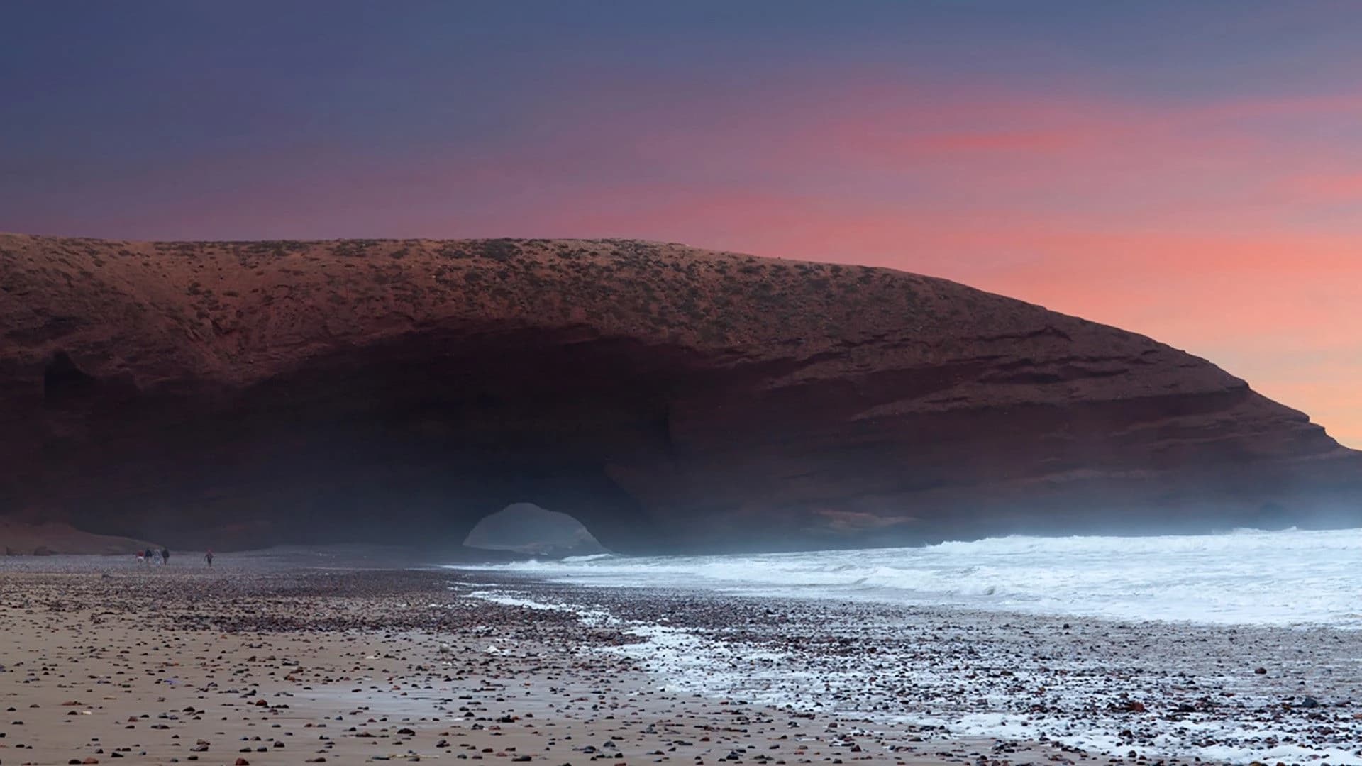 Sunset sky over the red cliffs and breaking waves at Legzira Beach