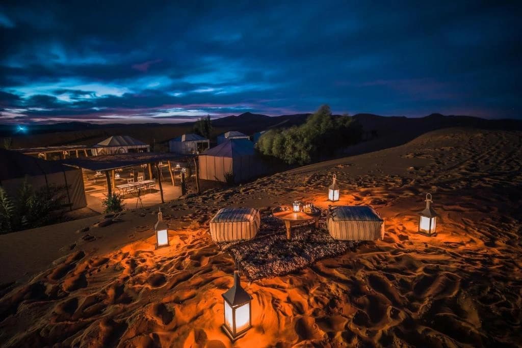 Lanterns lighting tents and floor seating at the desert camp at night