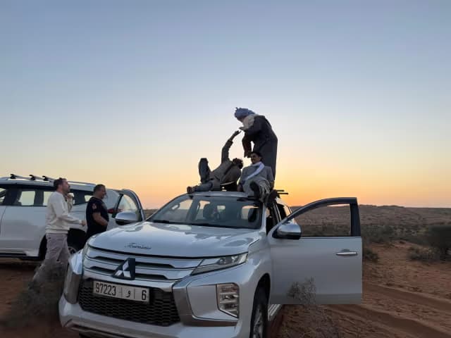 Four-wheel-drive vehicles parked in the desert at sunset