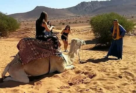 Traveler riding a camel led by a guide in the desert